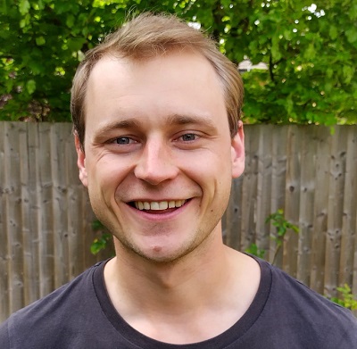Smiling man in tshirt standing in front of fence